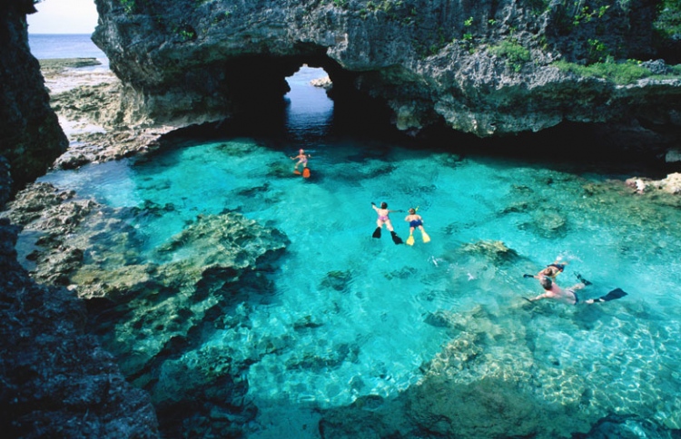 swimmers snorkeling in the cerulean waters of niues rock pools.